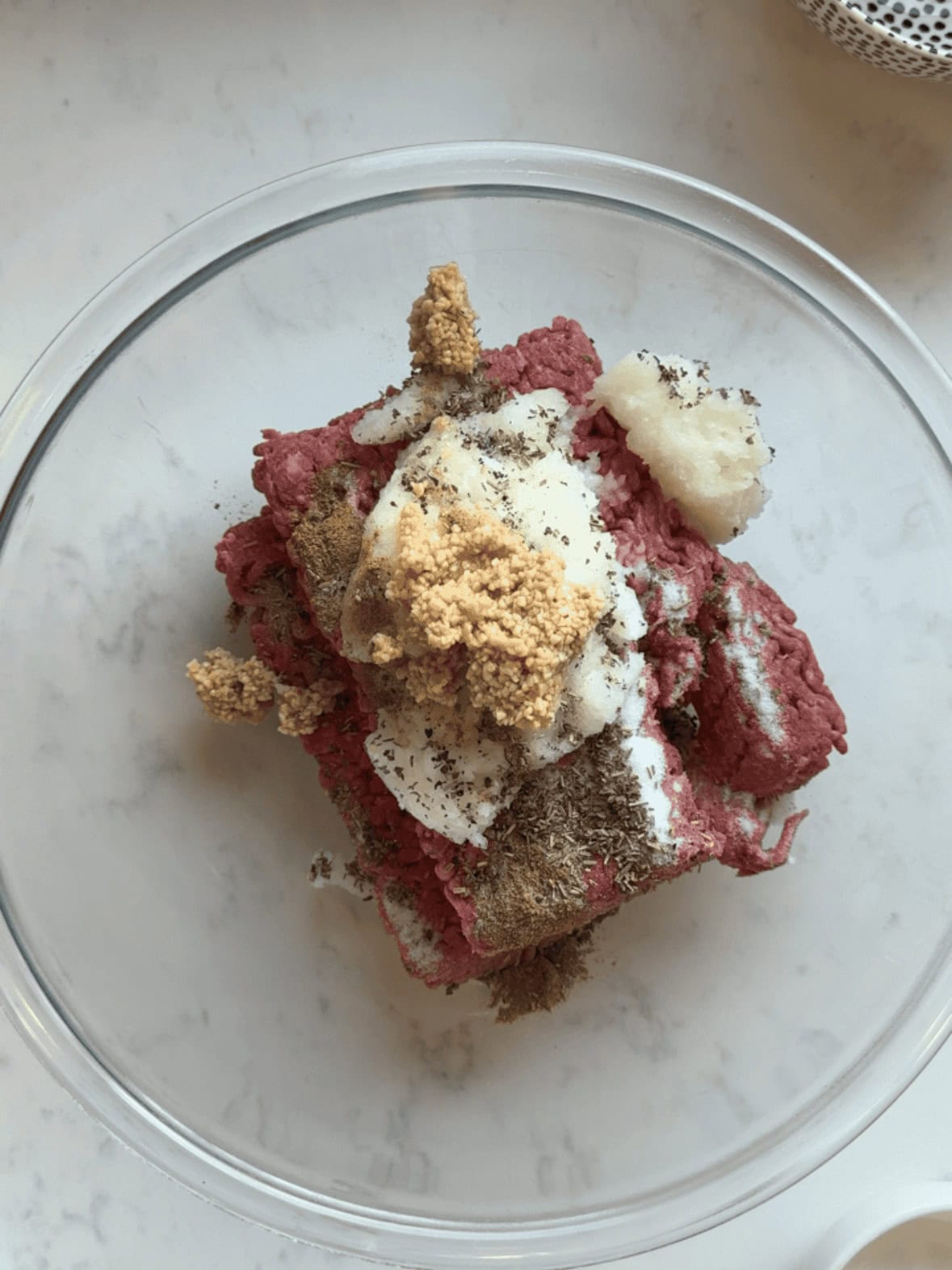 Ground beef mixed with puréed onion, garlic, and Greek gyro seasoning in a bowl