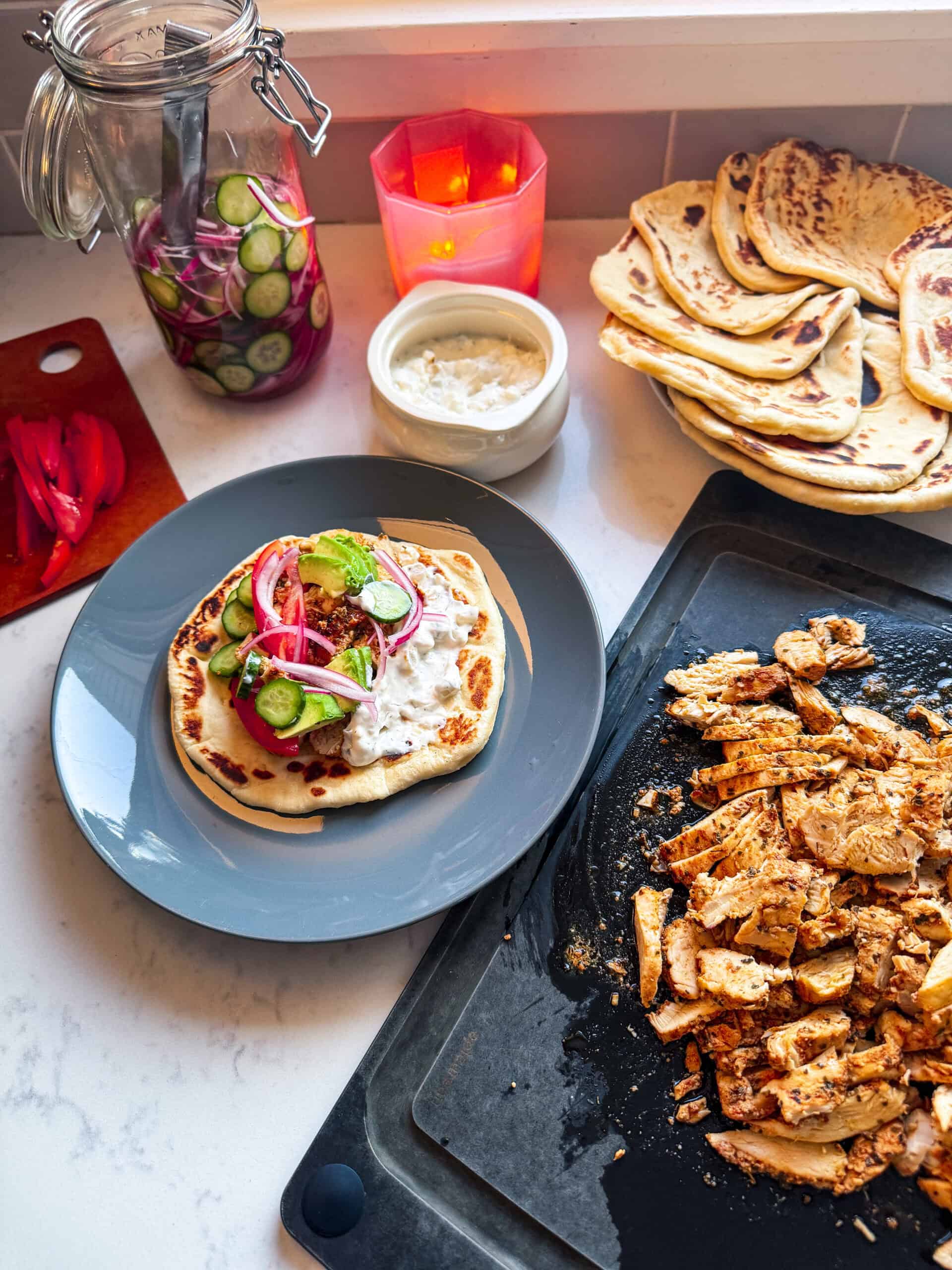 Chicken flatbread topped with quick pickled red onions and cucumbers beside jar of pickles
