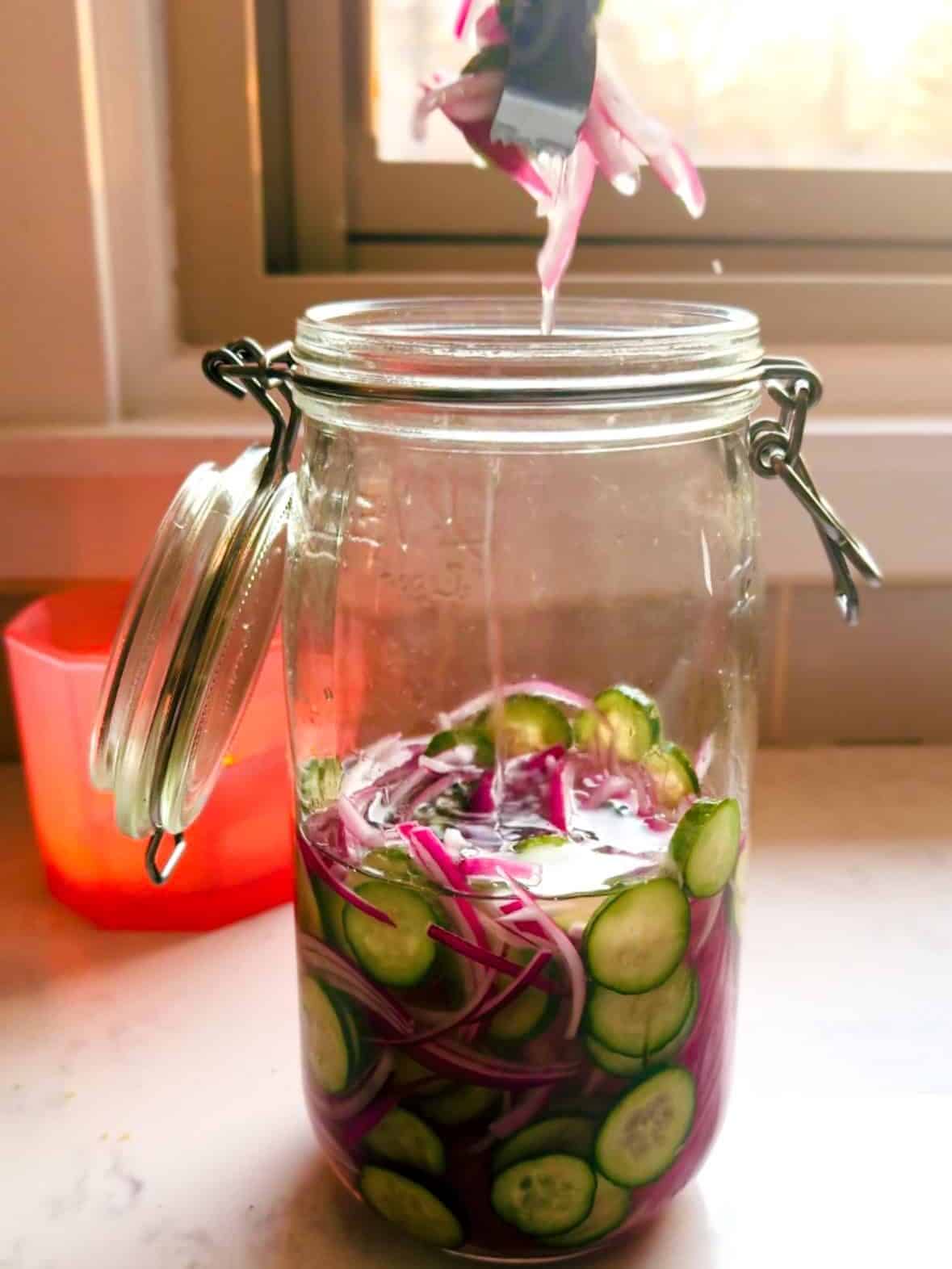 Removing quick pickled red onions and cucumbers from a mason jar using a fork