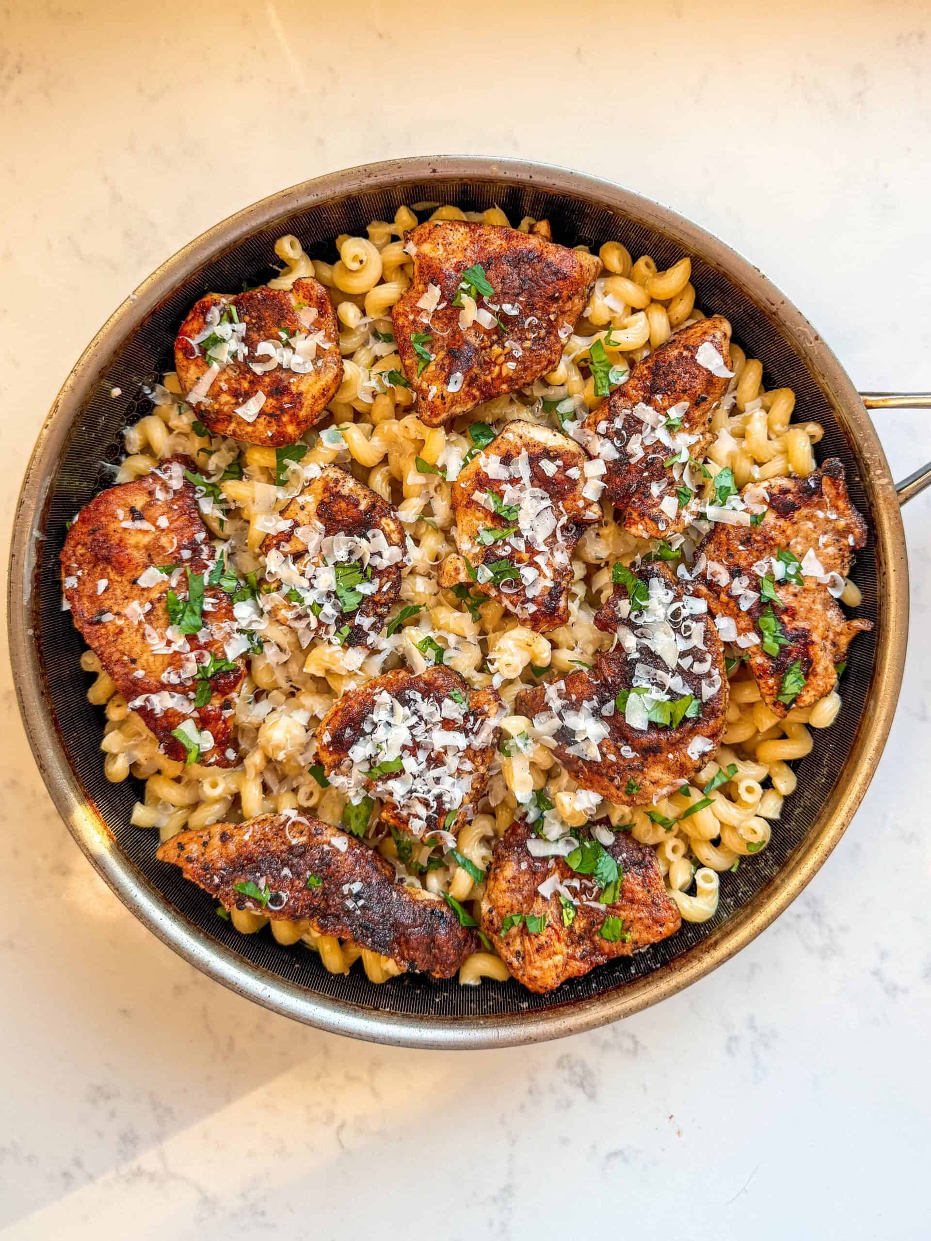 Garlic parmesan chicken pasta served in a skillet with creamy parmesan sauce and parsley garnish