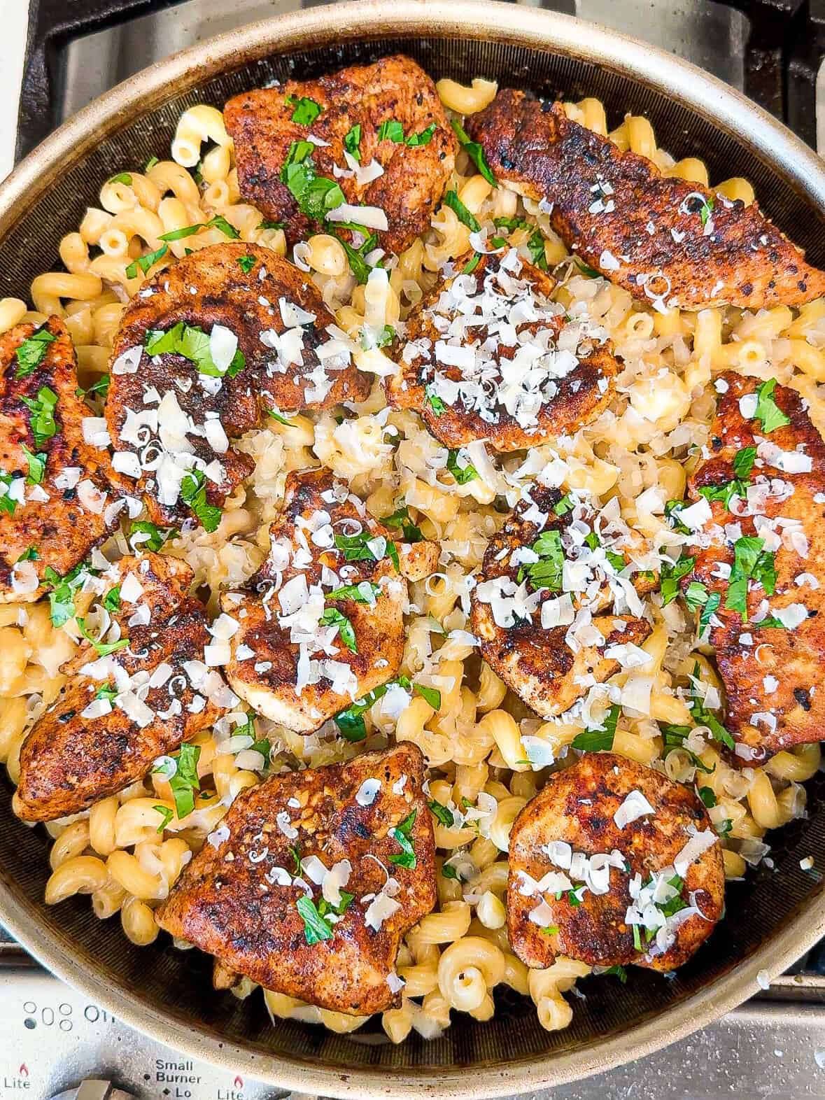 Garlic parmesan chicken pasta with parsley and parmesan cheese in a skillet on the stove