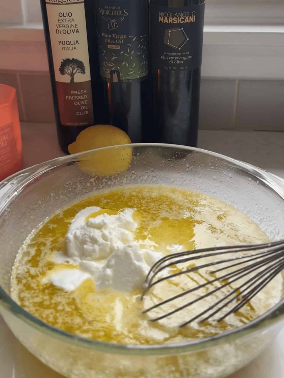 Wet ingredients for olive oil Bundt cake in a bowl with olive oil nearby