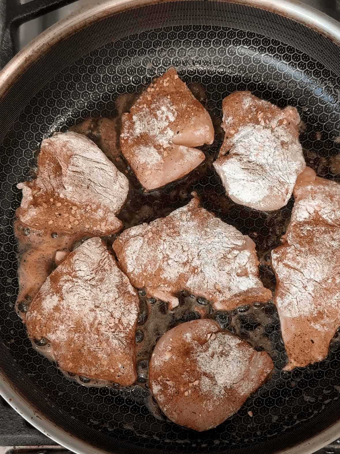 Chicken browning in a skillet with butter for garlic parmesan chicken pasta