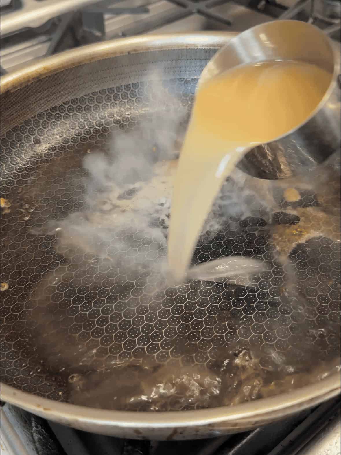 Deglazing the pan with chicken broth for garlic parmesan chicken pasta sauce