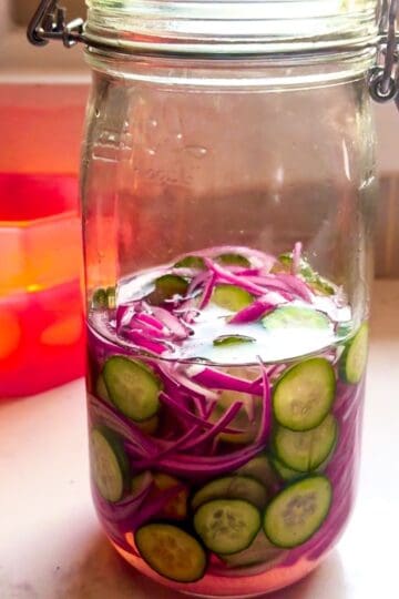 Close-up of mason jar filled with quick pickled red onions and cucumbers