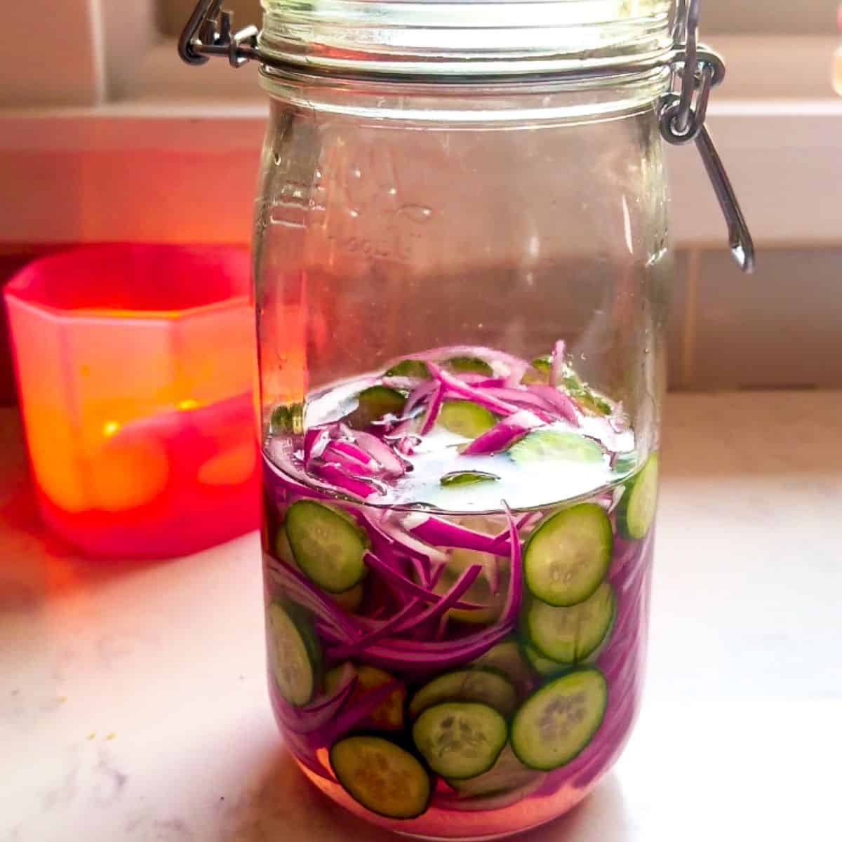 Close-up of mason jar filled with quick pickled red onions and cucumbers