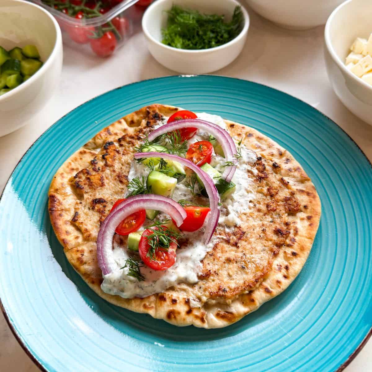 Greek smashed chicken taco surrounded by fresh Mediterranean toppings