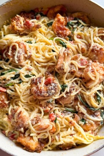 Overhead view of shrimp and spinach pasta with roasted red peppers and parmesan cheese