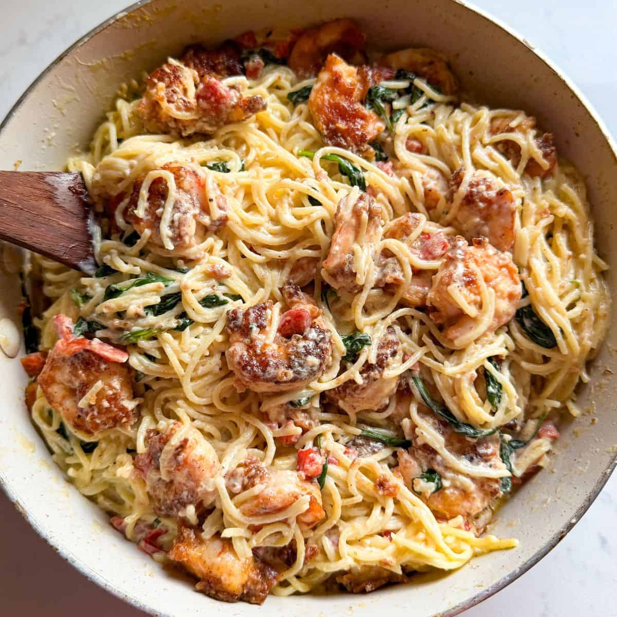 Overhead view of shrimp and spinach pasta with roasted red peppers and parmesan cheese