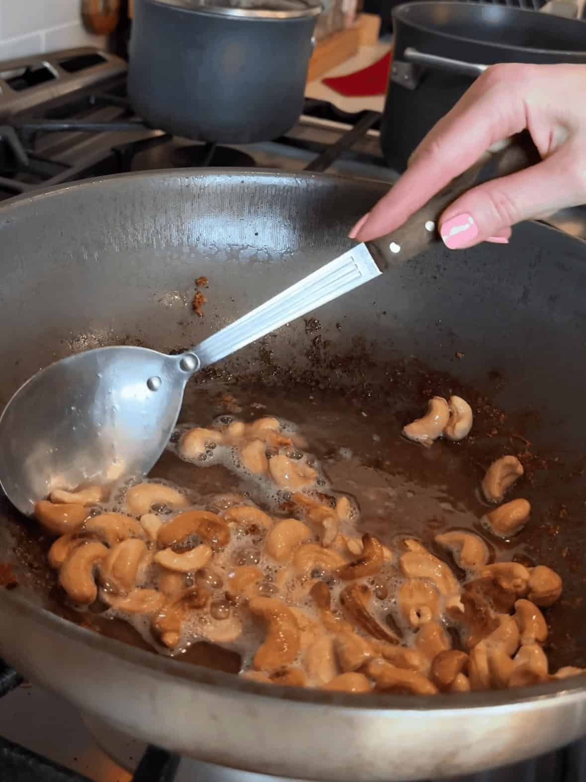 Toasting unsalted cashews in wok for homemade cashew chicken and peppers