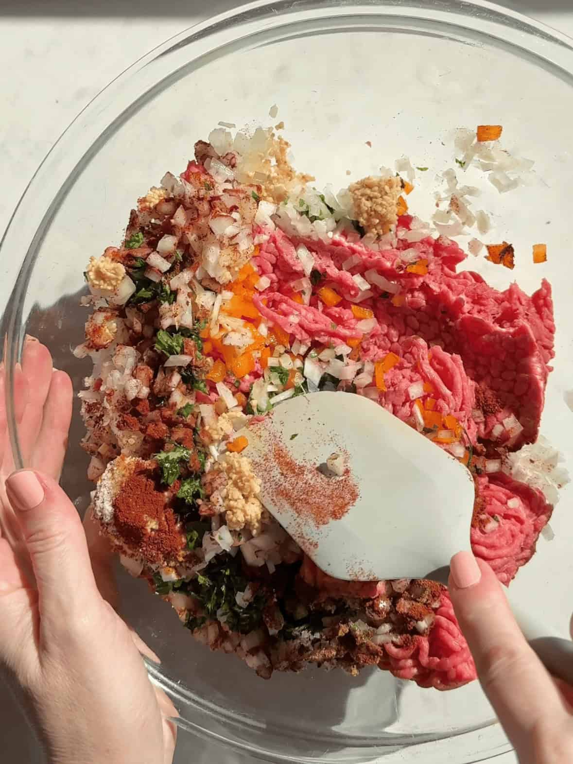 Mixing ground beef parsley garlic onion and spices in a bowl to make kofta mixture