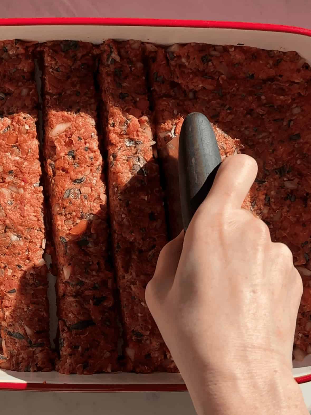 Ground beef kofta mixture pressed into casserole dish and shaped into long kebab rows