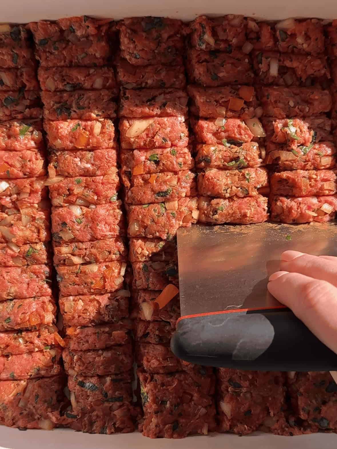 Scoring ground beef kofta in casserole dish to create traditional kebab texture before baking