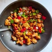 Overhead view of copycat cashew chicken and peppers in a wok with crispy chicken and vegetables