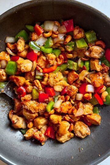 Overhead view of copycat cashew chicken and peppers in a wok with crispy chicken and vegetables