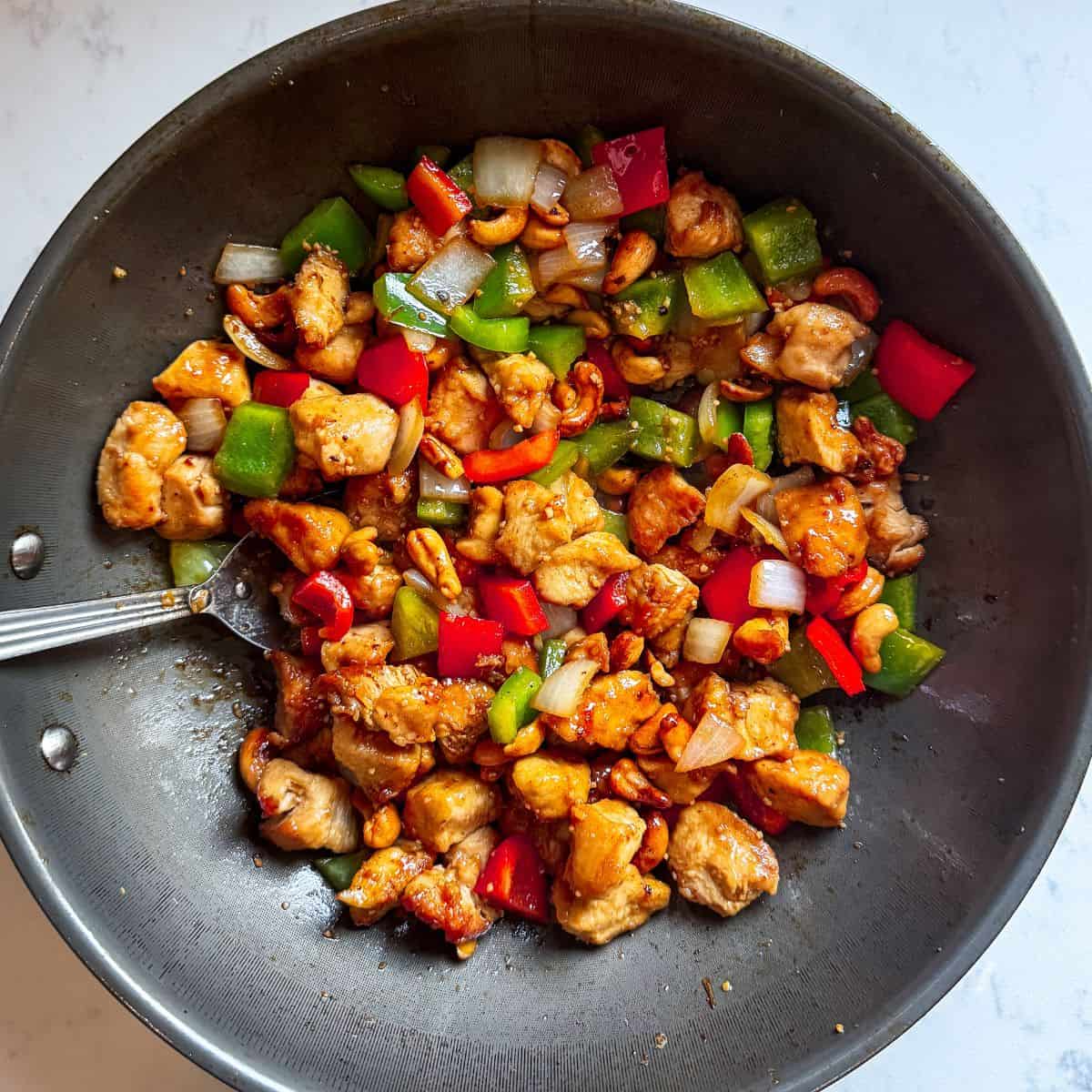Overhead view of copycat cashew chicken and peppers in a wok with crispy chicken and vegetables