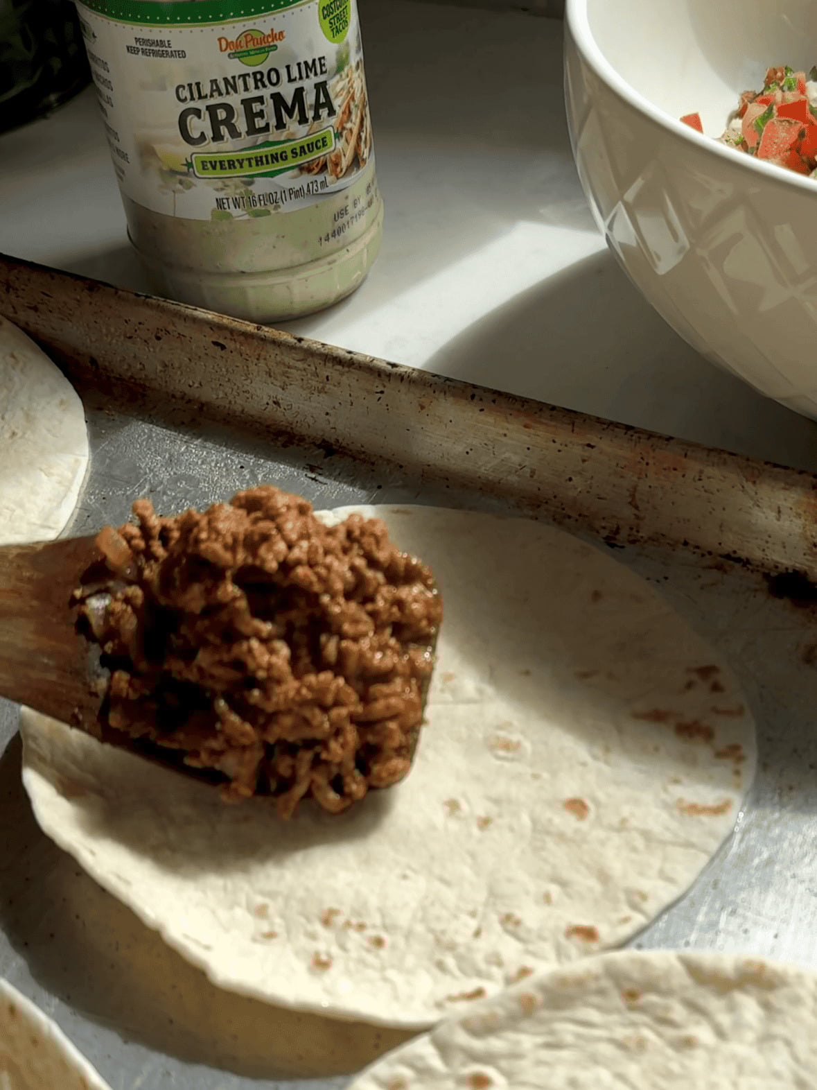 assembling flour tortillas with ground beef and cheese for crispy baked tacos