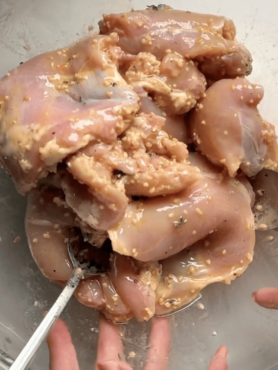 Chicken thighs marinating in lemon Dijon, olive oil, garlic, and thyme for one pan chicken thighs and veggies