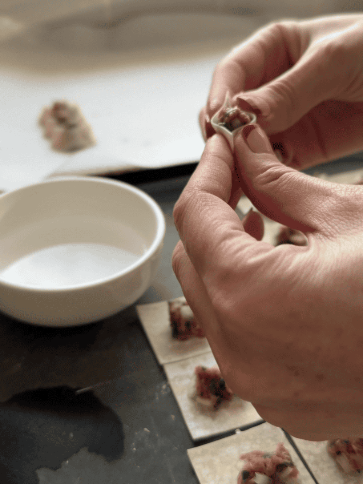 Seasoned meat filling placed inside wonton wrapper squares to shape Armenian Manti boats.