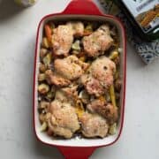 Overhead view of one pan chicken thighs and veggies with baby potatoes, rainbow carrots, red onion, lemon, thyme, and feta