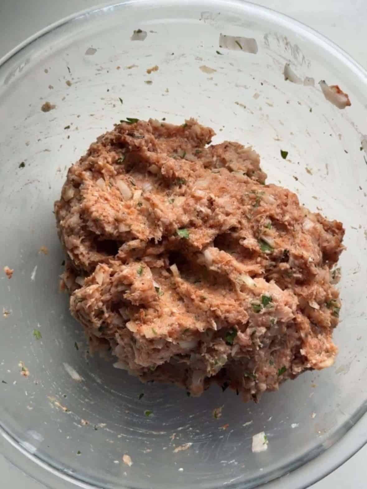 Seasoned ground chicken doner kabob mixture in a glass bowl showing sumac paprika cumin garlic and parsley mixed throughout