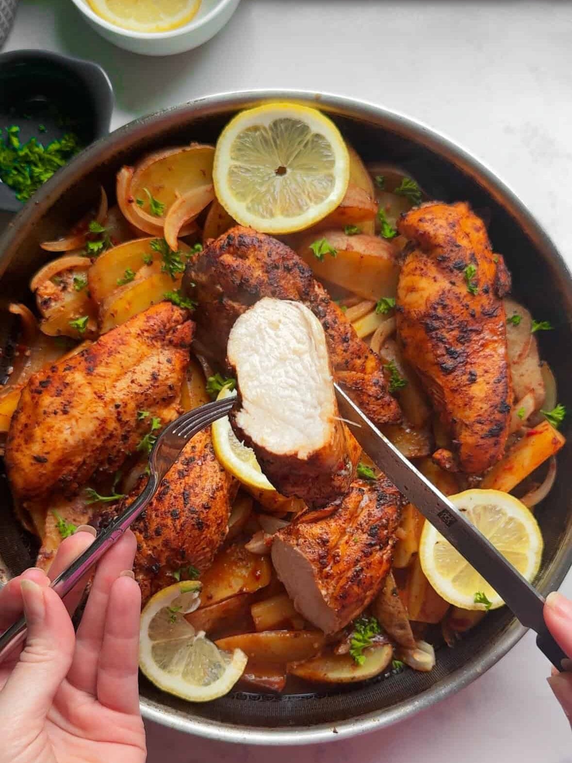 Hands slicing into a cooked Aleppo pepper chicken breast showing a juicy tender interior