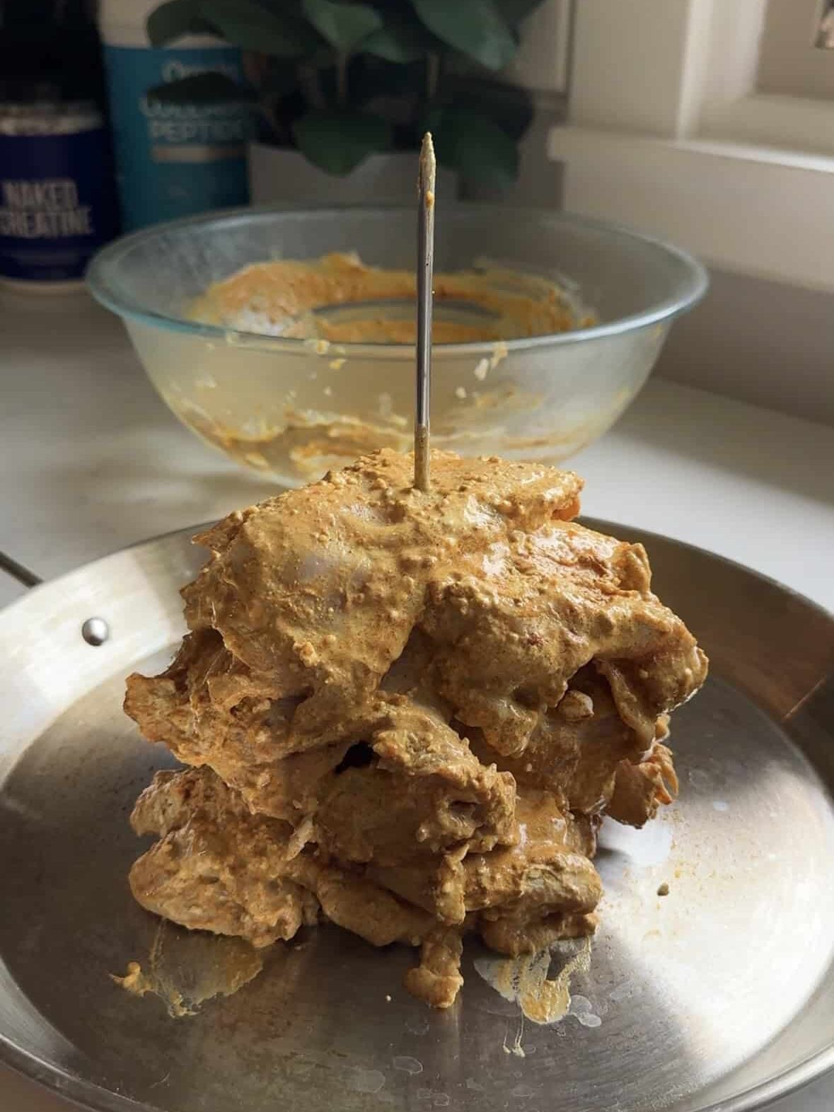 Boneless chicken thighs marinated in shawarma seasoning stacked on a vertical spit ready for the oven