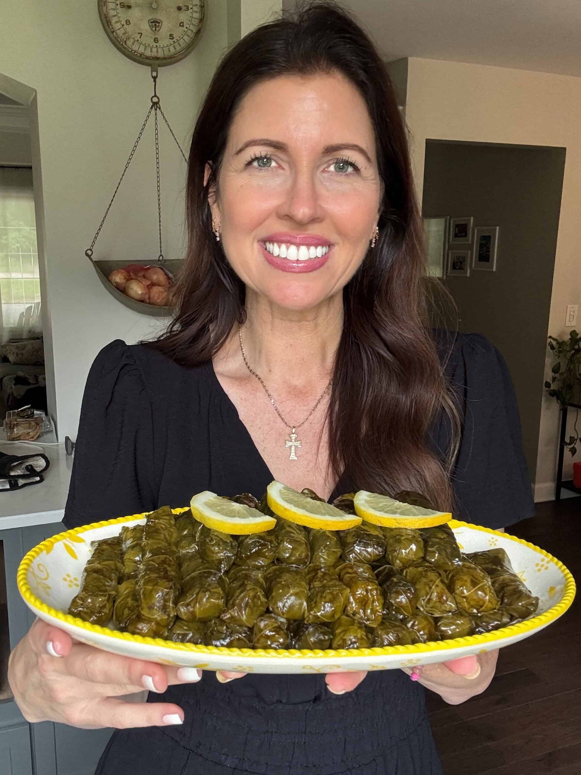 Woman holding a platter of vegetarian stuffed grape leaves garnished with lemon
