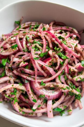 Close-up of sumac onion salad with parsley and olive oil in a white bowl