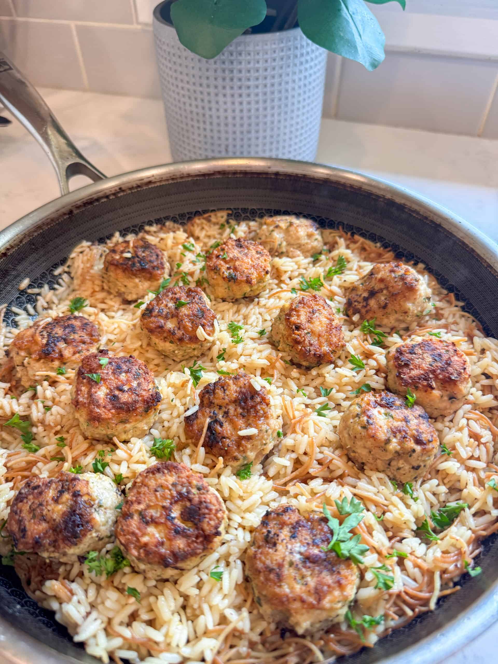Skillet of Greek chicken meatballs and rice pilaf on a kitchen counter, ready to serve