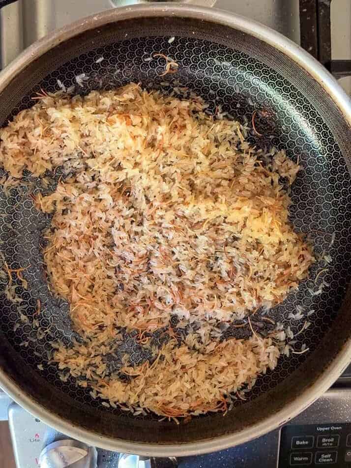 Toasted vermicelli noodles and rice cooking in a skillet for rice pilaf
