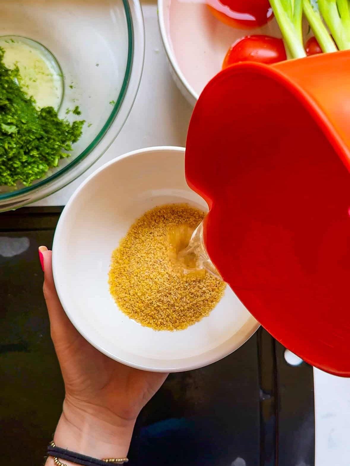 Measuring fine bulgur wheat into a bowl to make Levantine tabbouleh