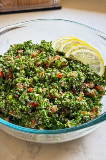 Close-up of parsley-forward Levantine tabbouleh in a glass serving bowl