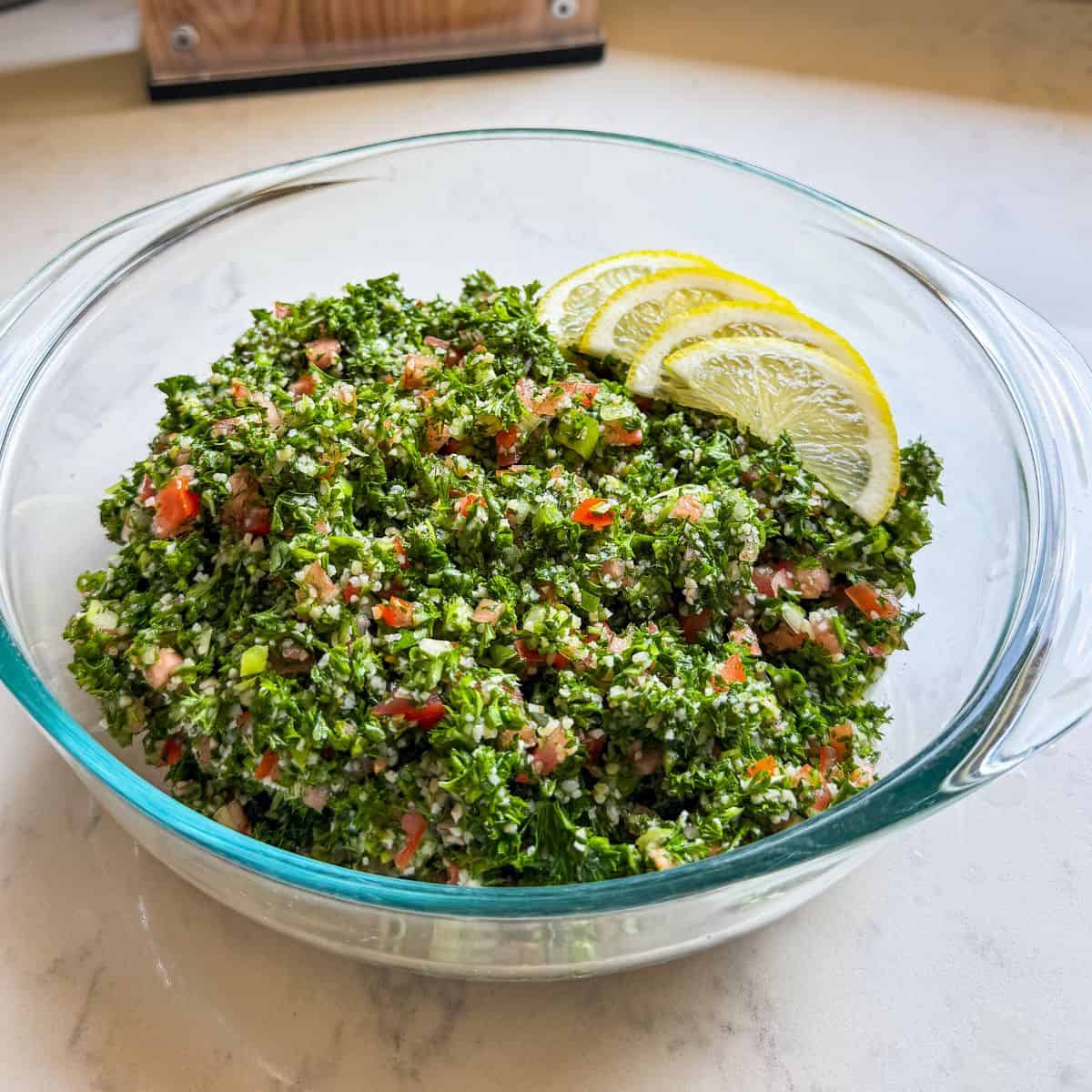 Close-up of parsley-forward Levantine tabbouleh in a glass serving bowl