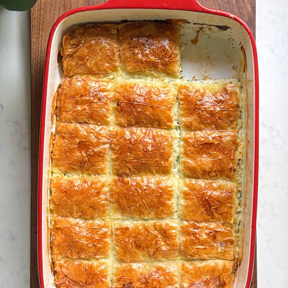 Armenian sheet cheese boreg baked golden and cut into squares in a red baking dish