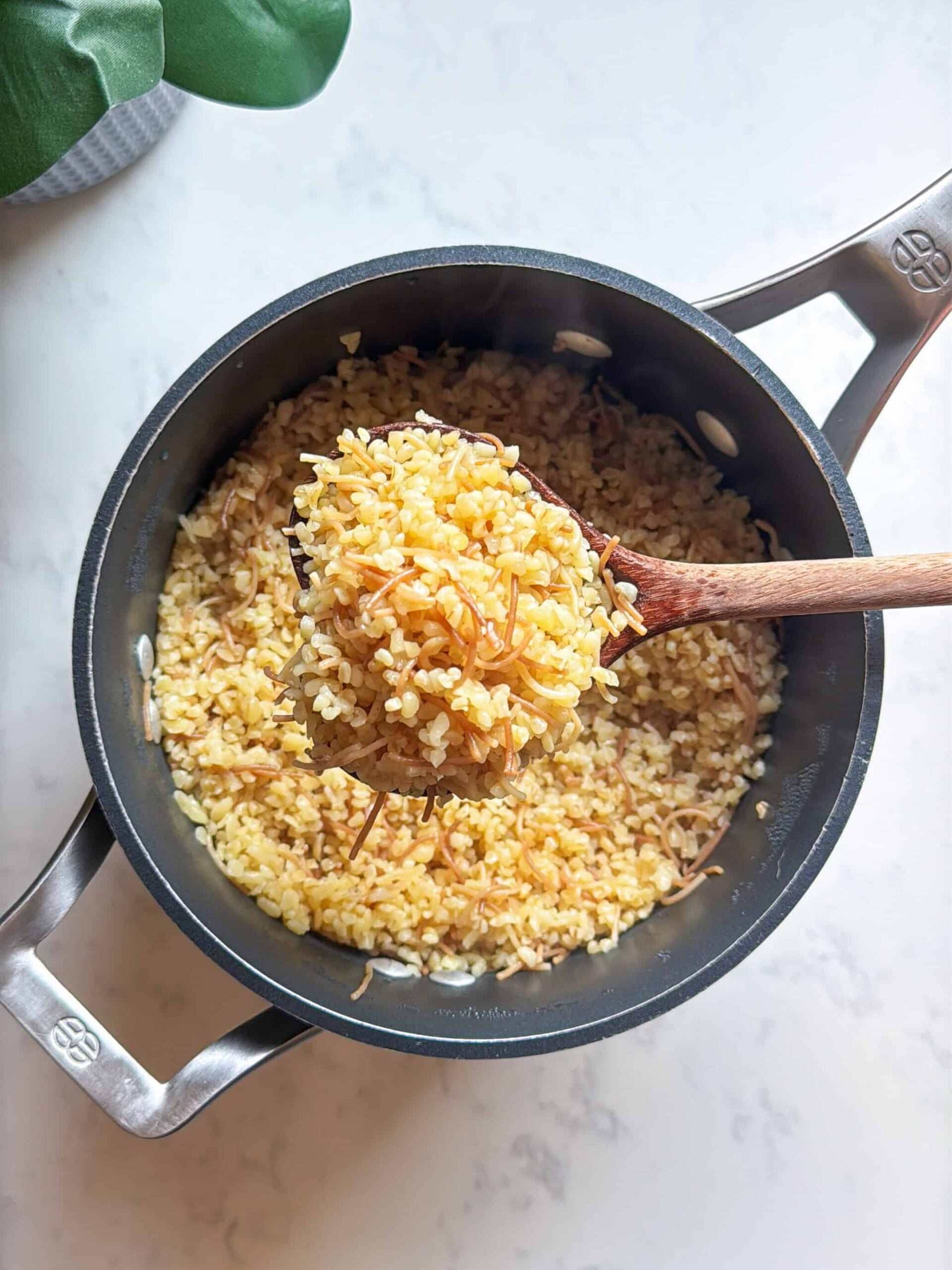 Spoonful of golden toasted bulgur and vermicelli lifted from a saucepan before adding broth
