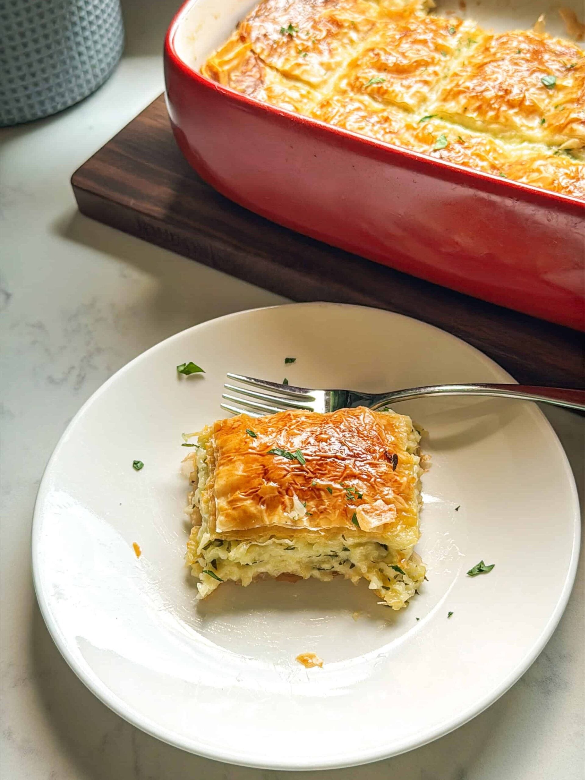 A slice of Armenian sheet cheese boreg plated next to the baking dish