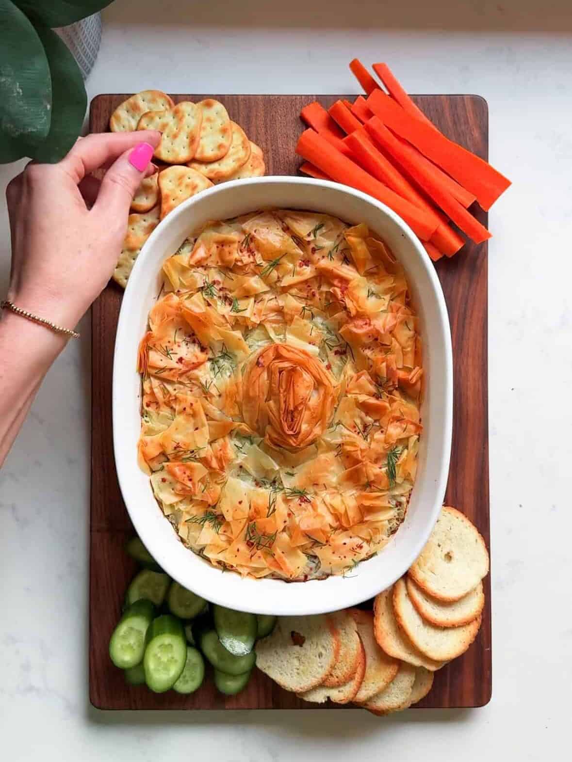 Reaching for a cracker to dip into baked spanakopita dip