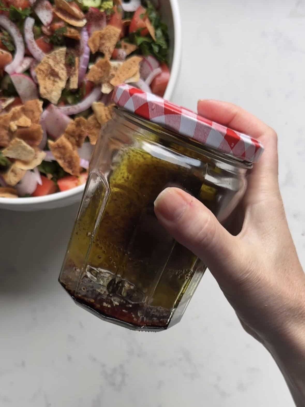 Shaking fresh lemon and pomegranate molasses dressing in a mason jar for fattoush salad