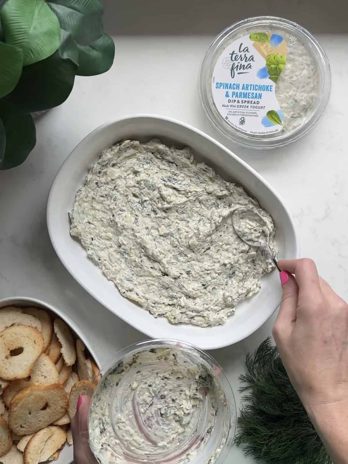 Spreading La Terra Fina spinach artichoke dip into a baking dish