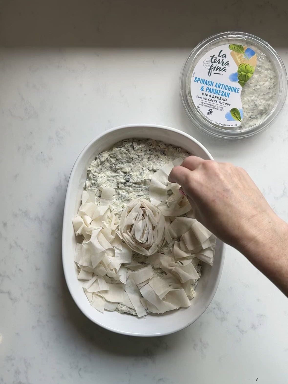 Arranging torn phyllo pieces and a phyllo spiral over spinach artichoke dip