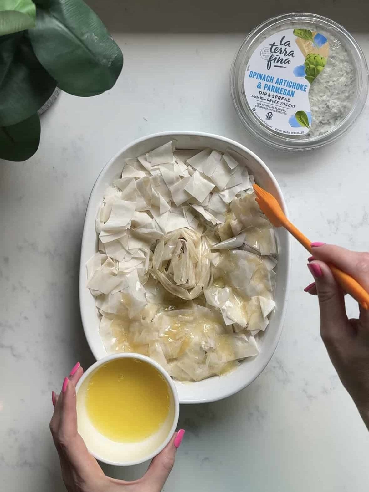 Brushing melted butter over the phyllo spiral before baking spanakopita dip