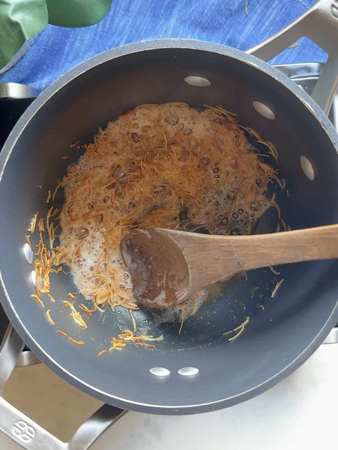 Vermicelli noodles toasting in butter until deep golden brown in a saucepan