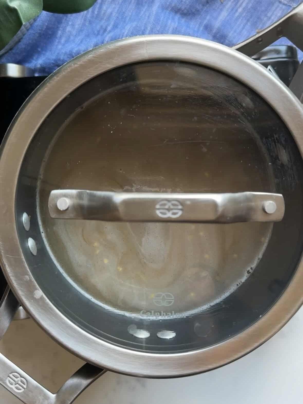 Glass lid on a saucepan with bulgur pilaf simmering in chicken broth