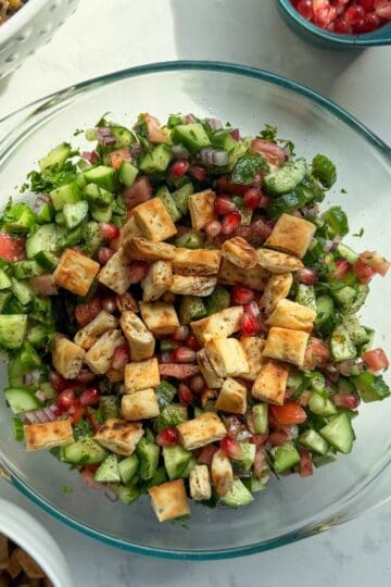 Mediterranean chopped salad with sumac topped with pomegranate seeds and toasted pita