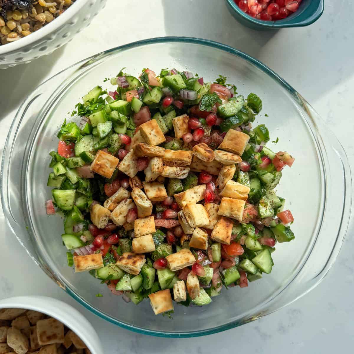 Mediterranean chopped salad with sumac topped with pomegranate seeds and toasted pita