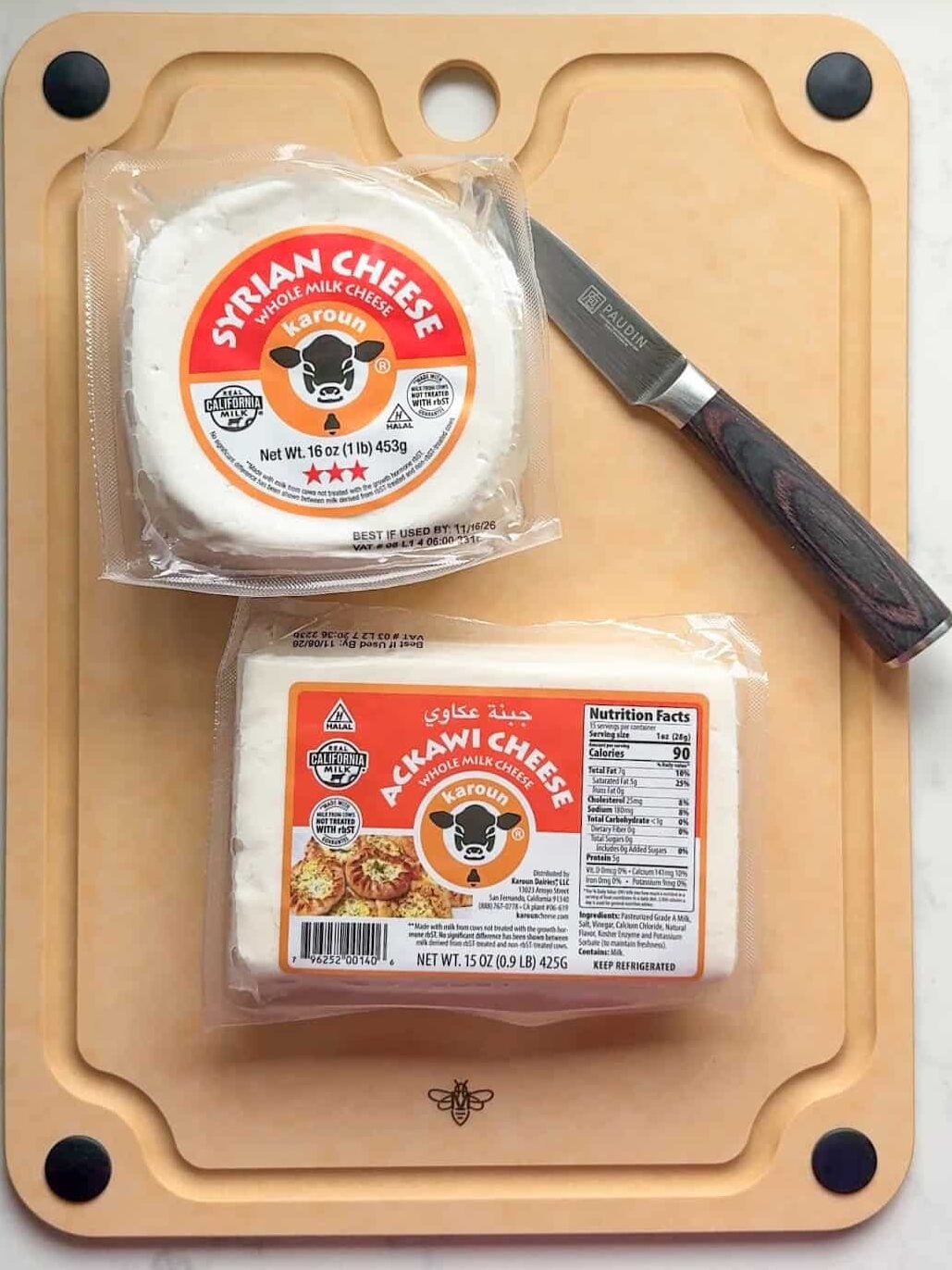 Packages of Karoun Syrian cheese and Ackawi cheese on a cutting board with a knife