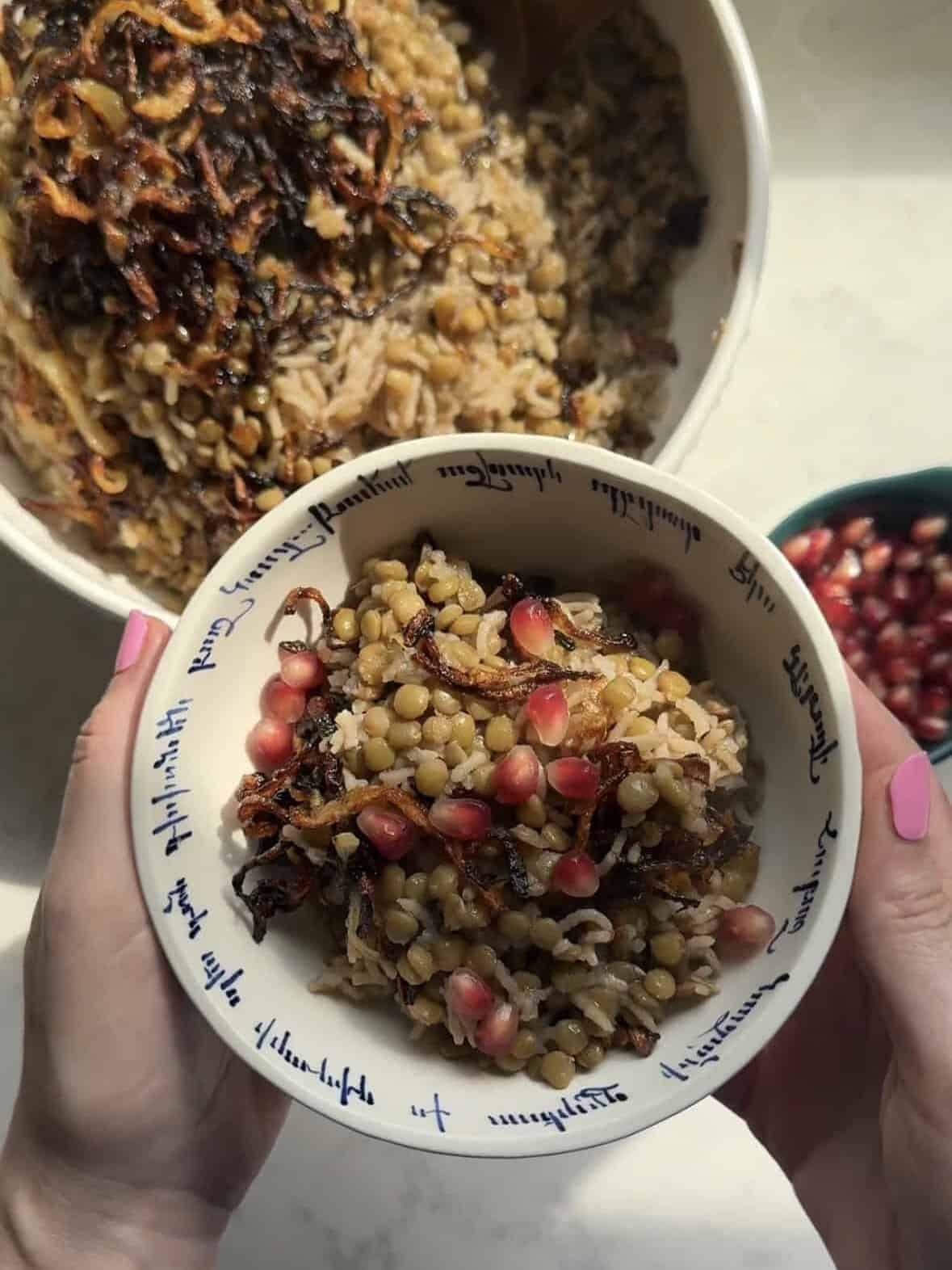 Close up of a single serving of mujadara with pomegranate seeds in a decorative bowl