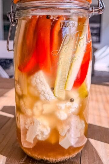 Jar of tourshi, Armenian pickled vegetables with cauliflower, red pepper, cucumber, and celery in a golden brine