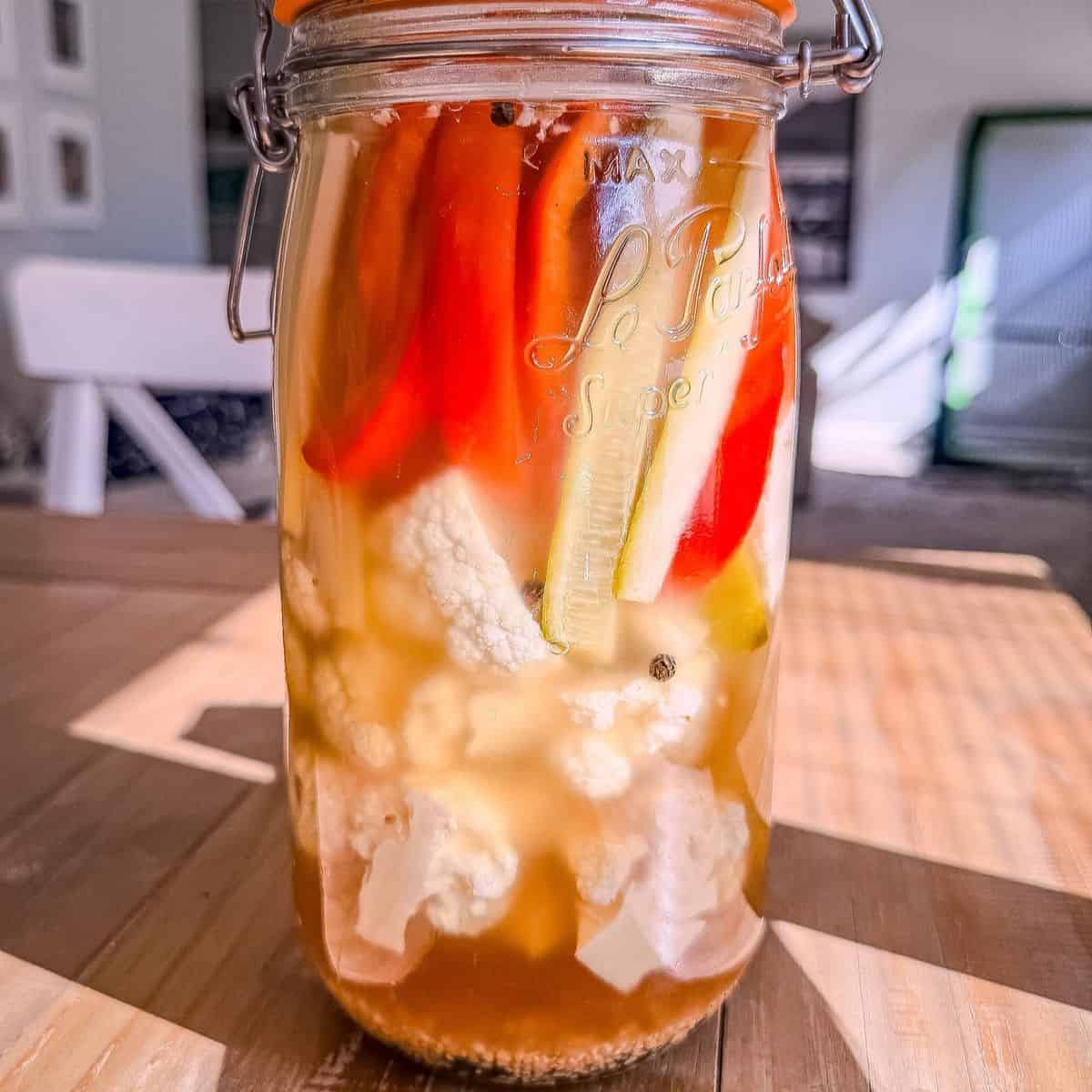 Jar of tourshi, Armenian pickled vegetables with cauliflower, red pepper, cucumber, and celery in a golden brine